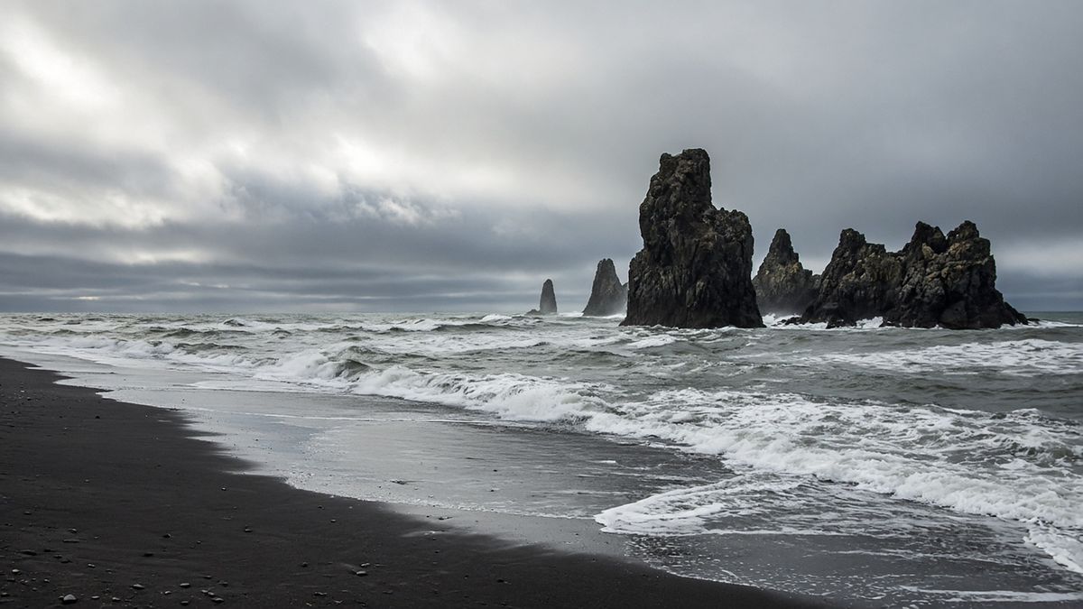 Black volcanic sand beach with basalt sea stacks and rolling surf